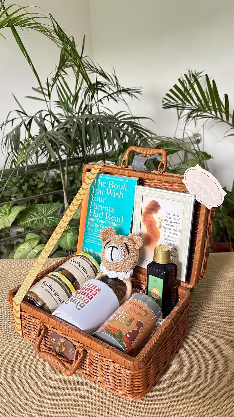 Wicker gift hamper containing pregnancy books, a teddy bear, and wellness products.