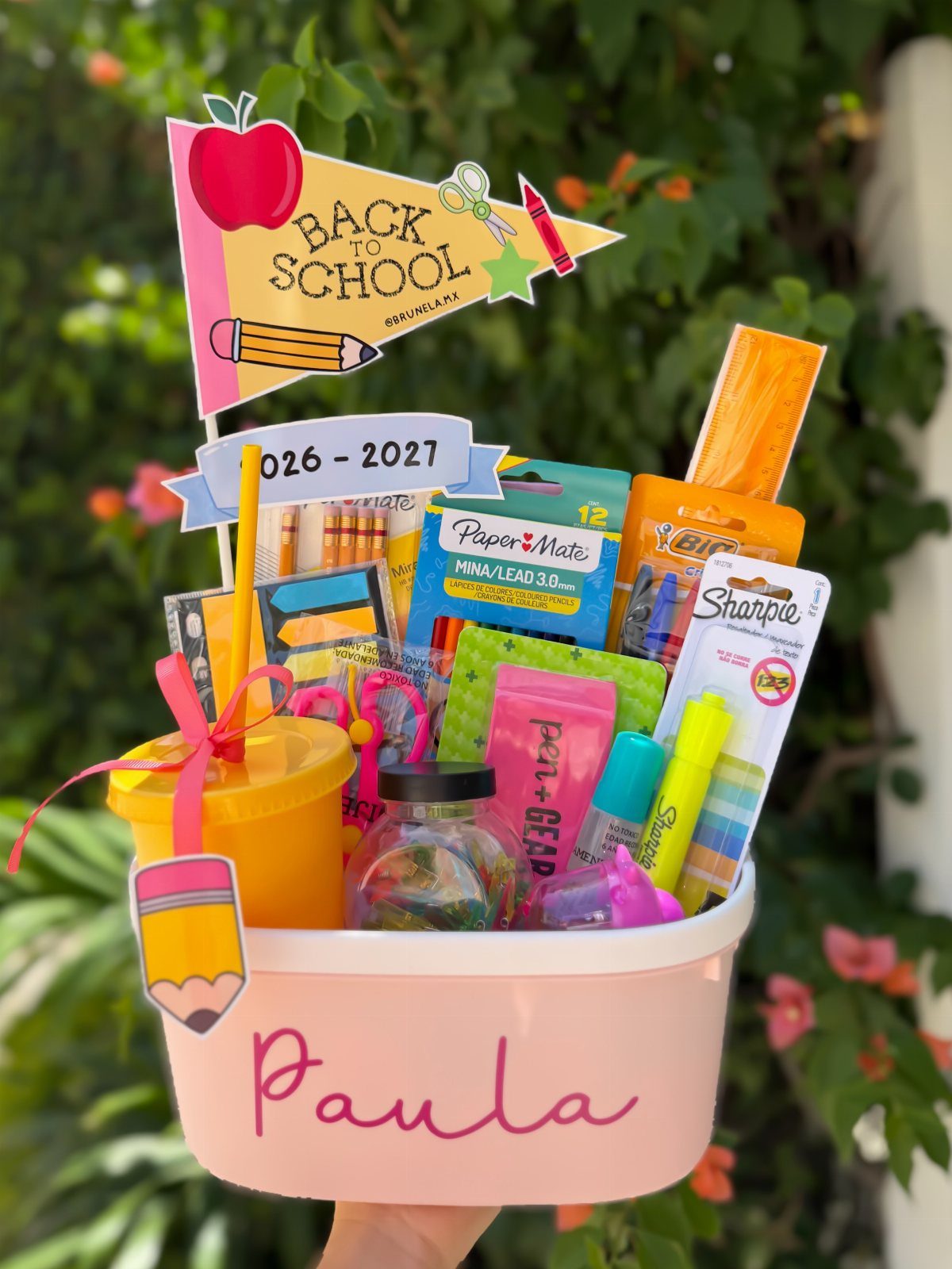 Pink bucket filled with school supplies and a Back to School sign.