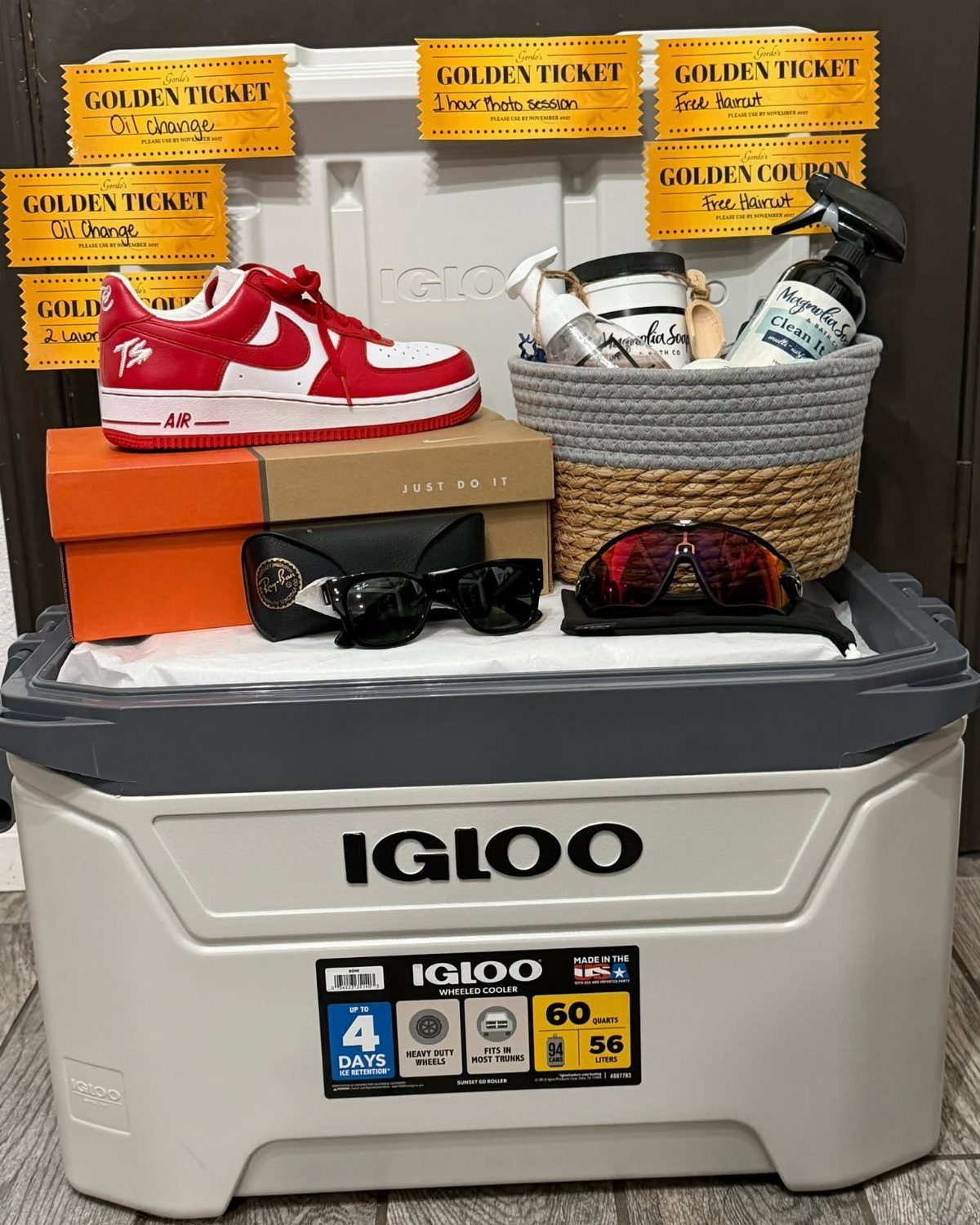 Igloo cooler raffle basket containing red sneakers, sunglasses, toiletries, and golden ticket vouchers.