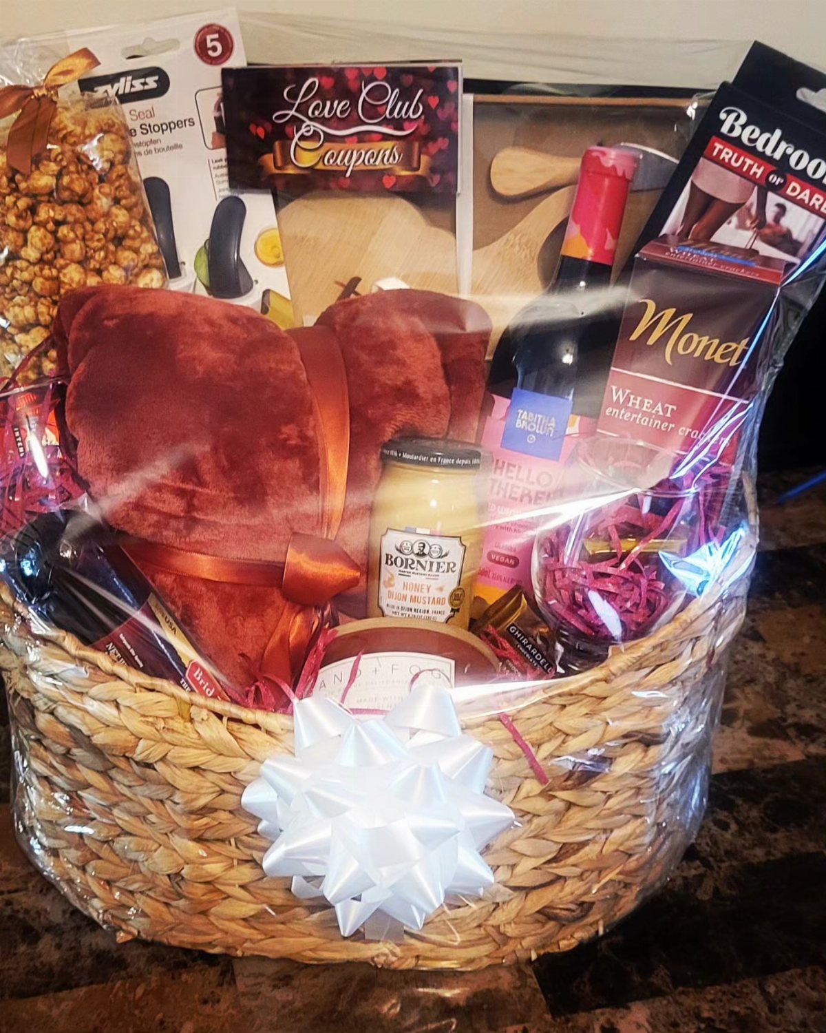 Wicker gift basket with wine, chocolates, and heart-shaped plush for a date night.