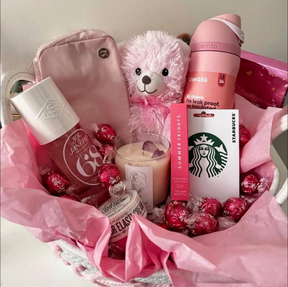 Pink themed gift basket with teddy bear, chocolates, and beauty products for Valentine's Day.