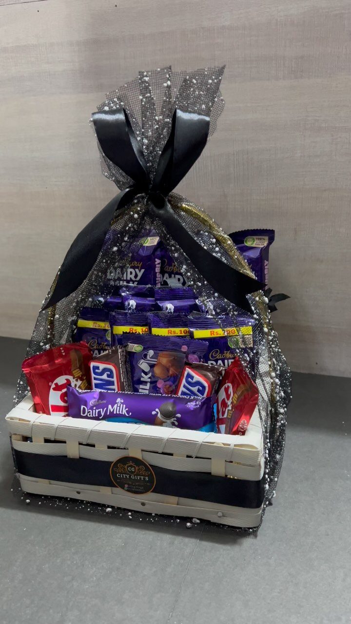 White wicker gift basket filled with assorted chocolate bars wrapped in silver mesh.