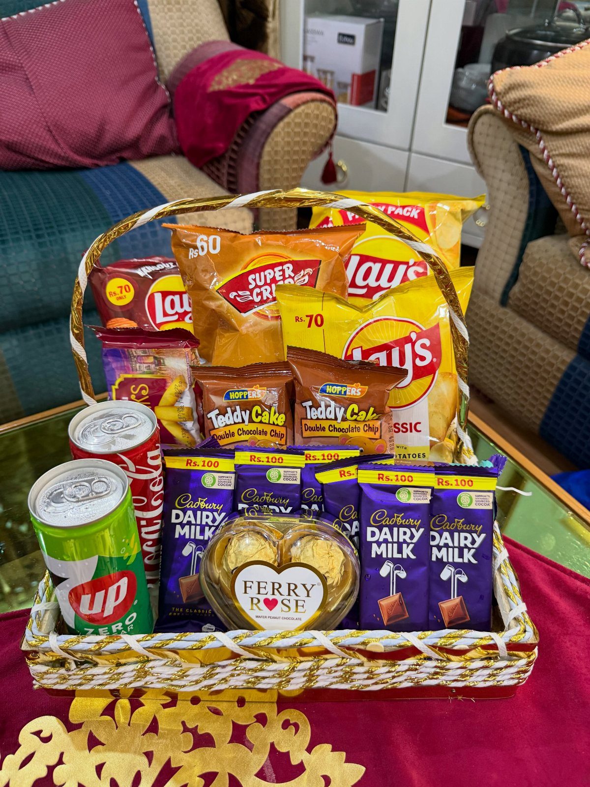 Woven gift basket filled with potato chips, chocolate bars, and soda cans.