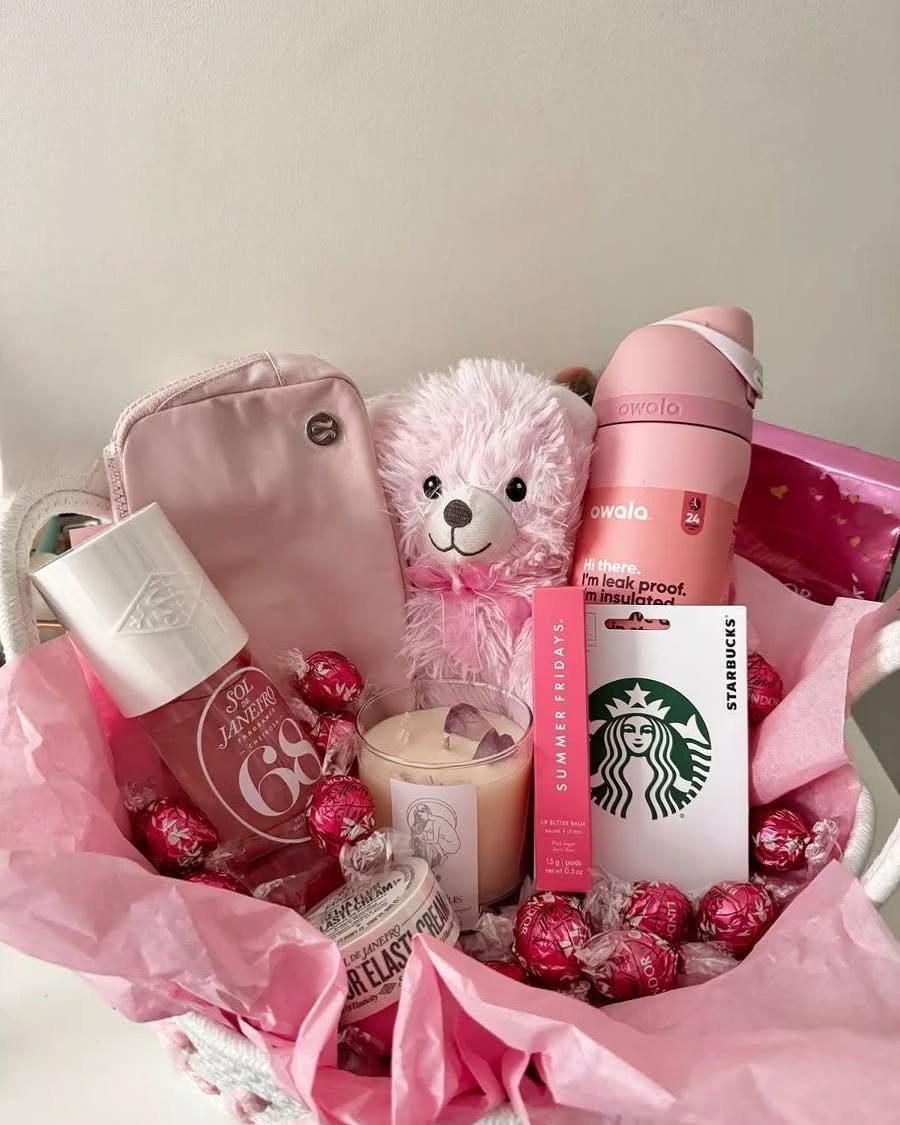 Pink themed gift basket with teddy bear, water bottle, candle, and Starbucks gift card.
