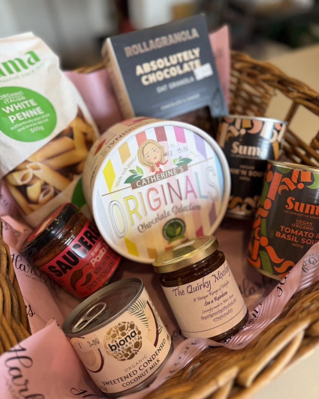 Wicker basket filled with gourmet pasta, chocolates, granola, and organic canned goods.