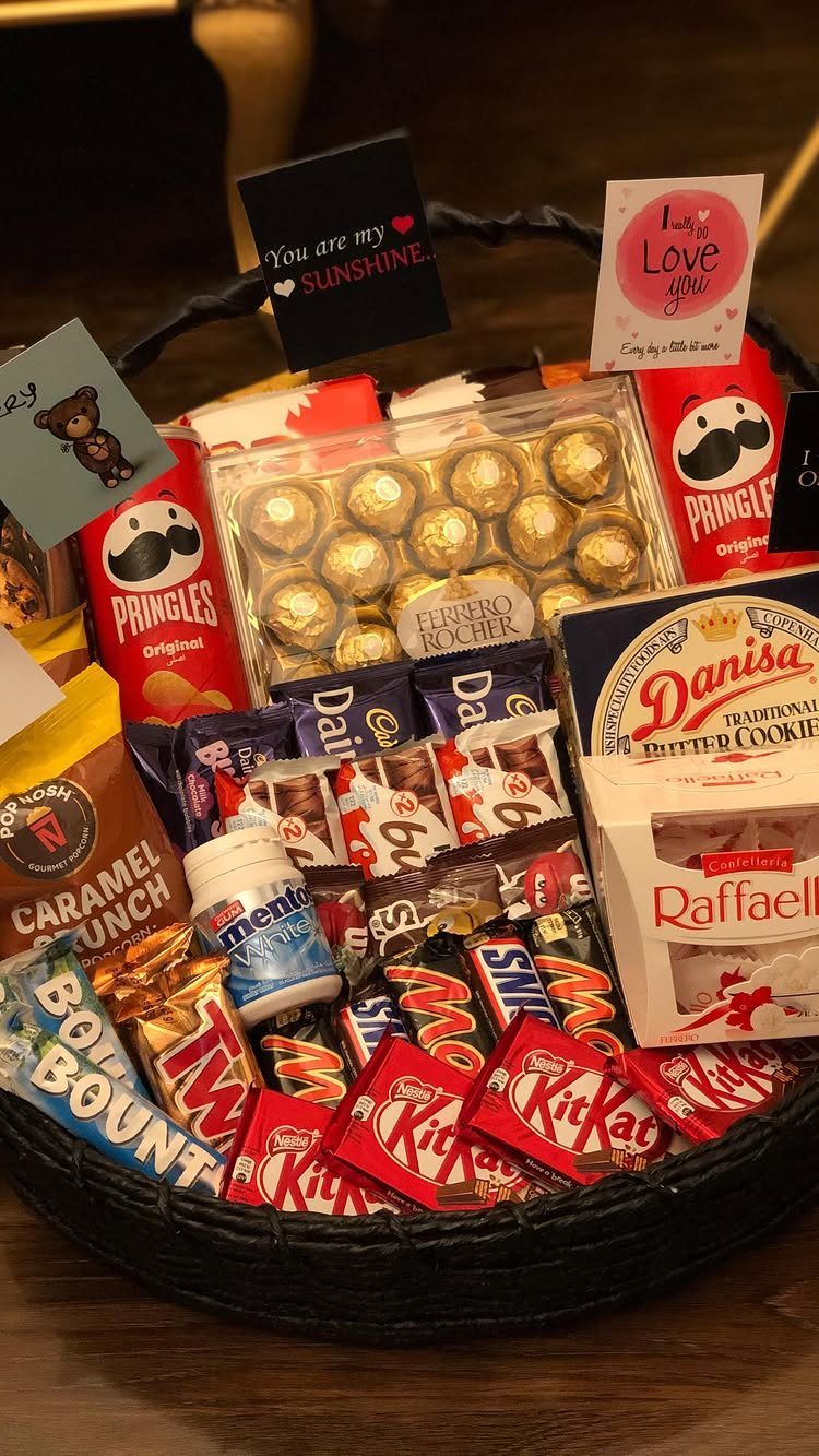 Gift basket filled with assorted chocolates, cookies, and chips with romantic note cards.