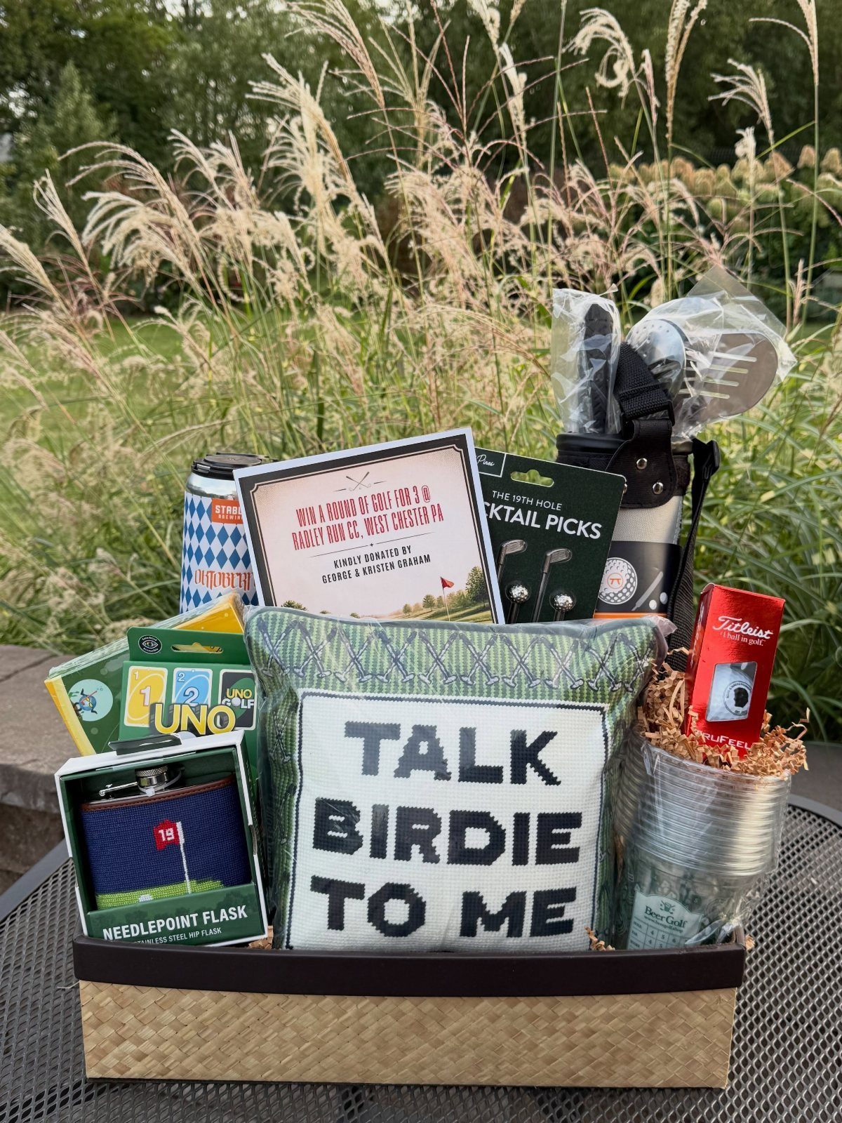Golf-themed raffle basket with a Talk Birdie To Me pillow and golf accessories.