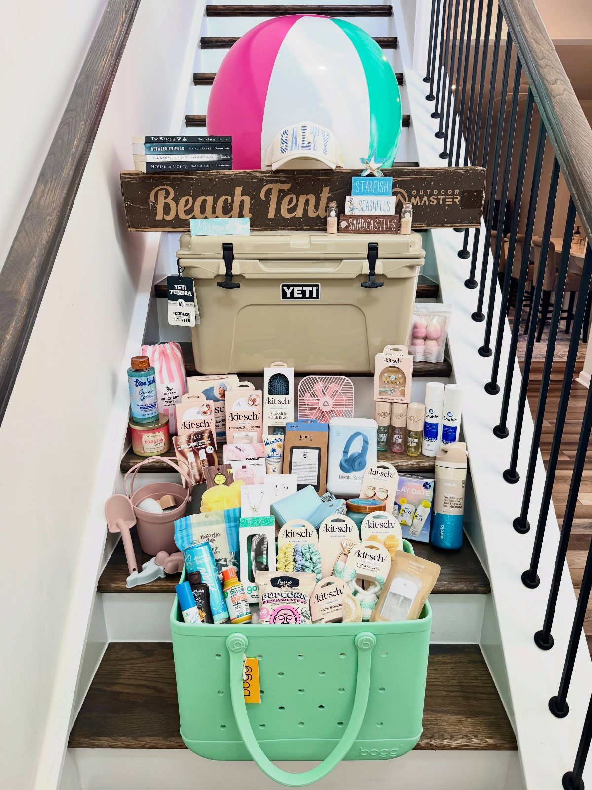 Beach-themed raffle basket with a Yeti cooler, beach ball, and sunscreen on stairs.