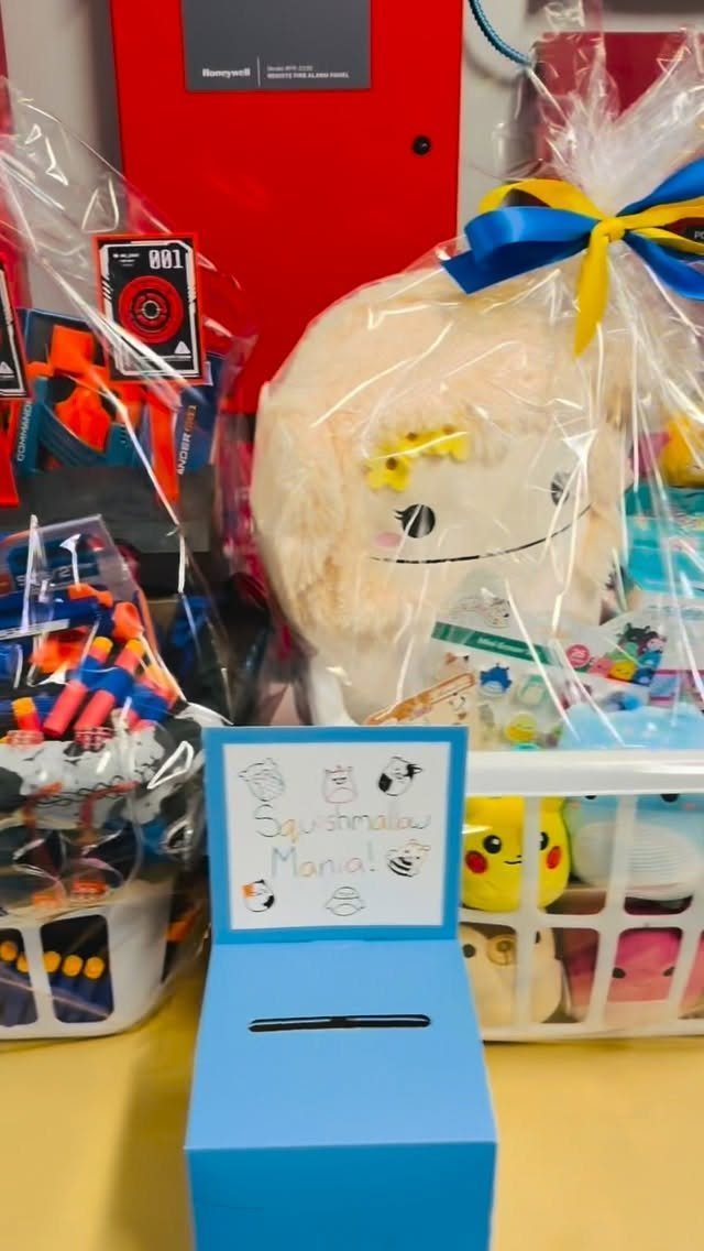 Raffle baskets with plush toys and markers next to a blue ticket box.