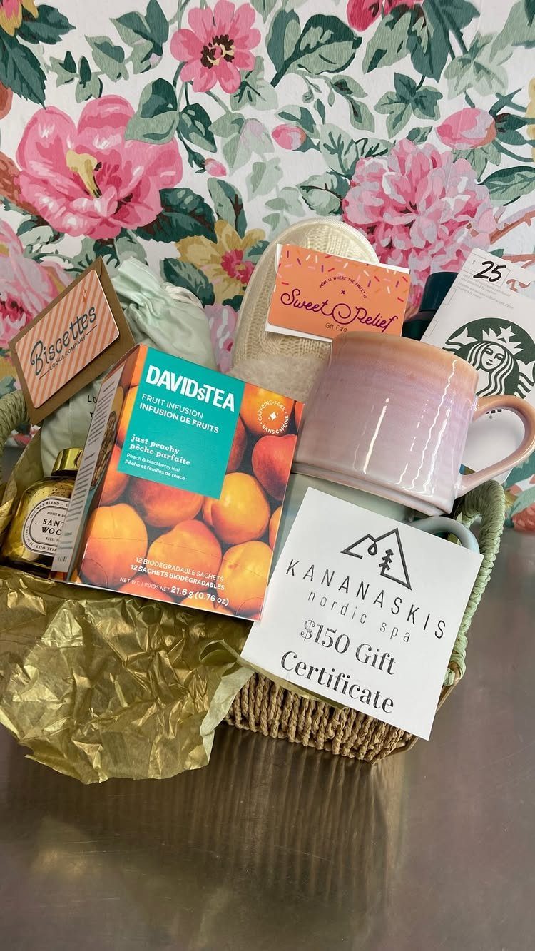 Wicker gift basket with tea, a pink mug, and a spa gift certificate.