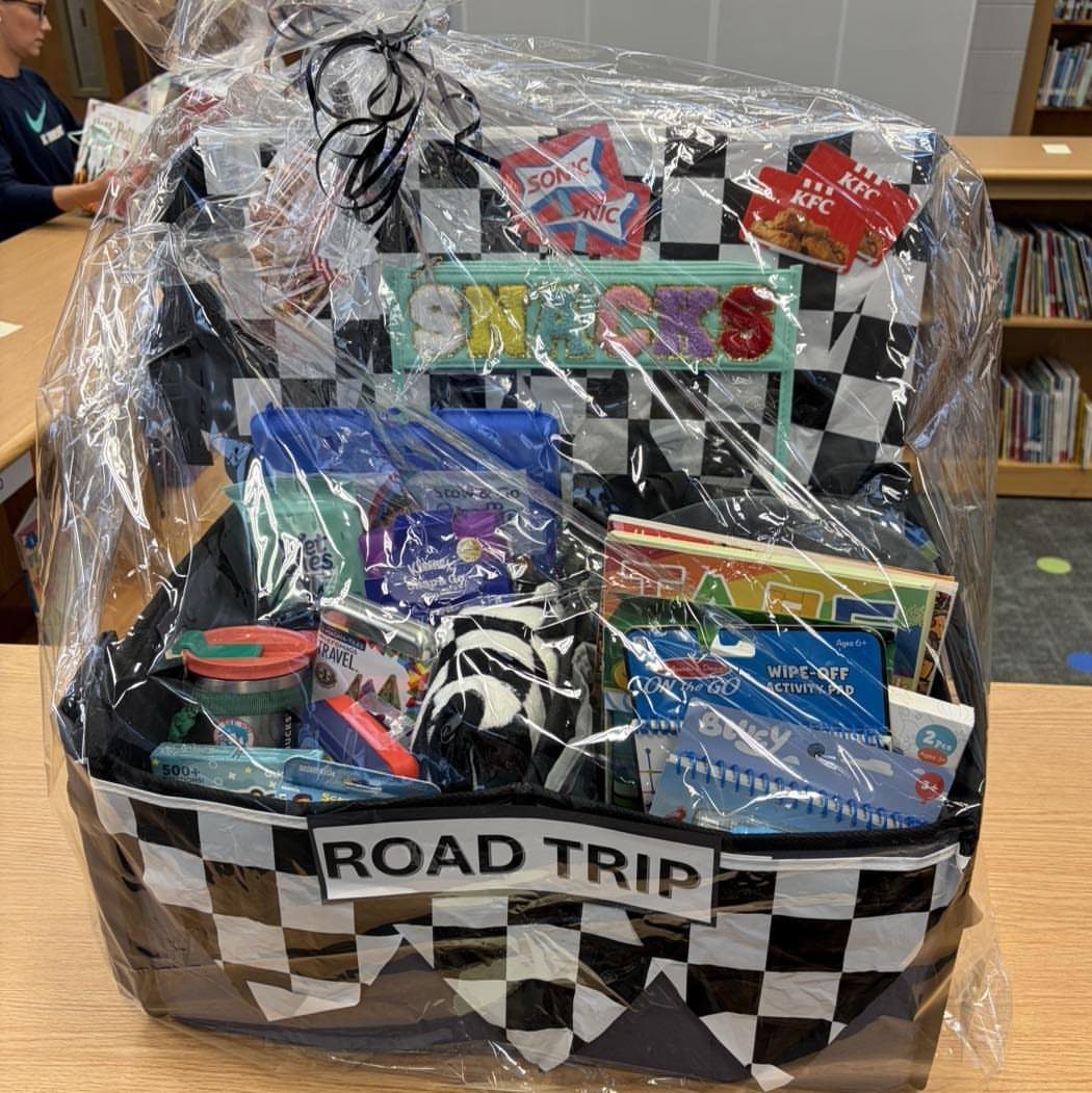 Road trip gift basket with checkered pattern containing snacks and travel activities.