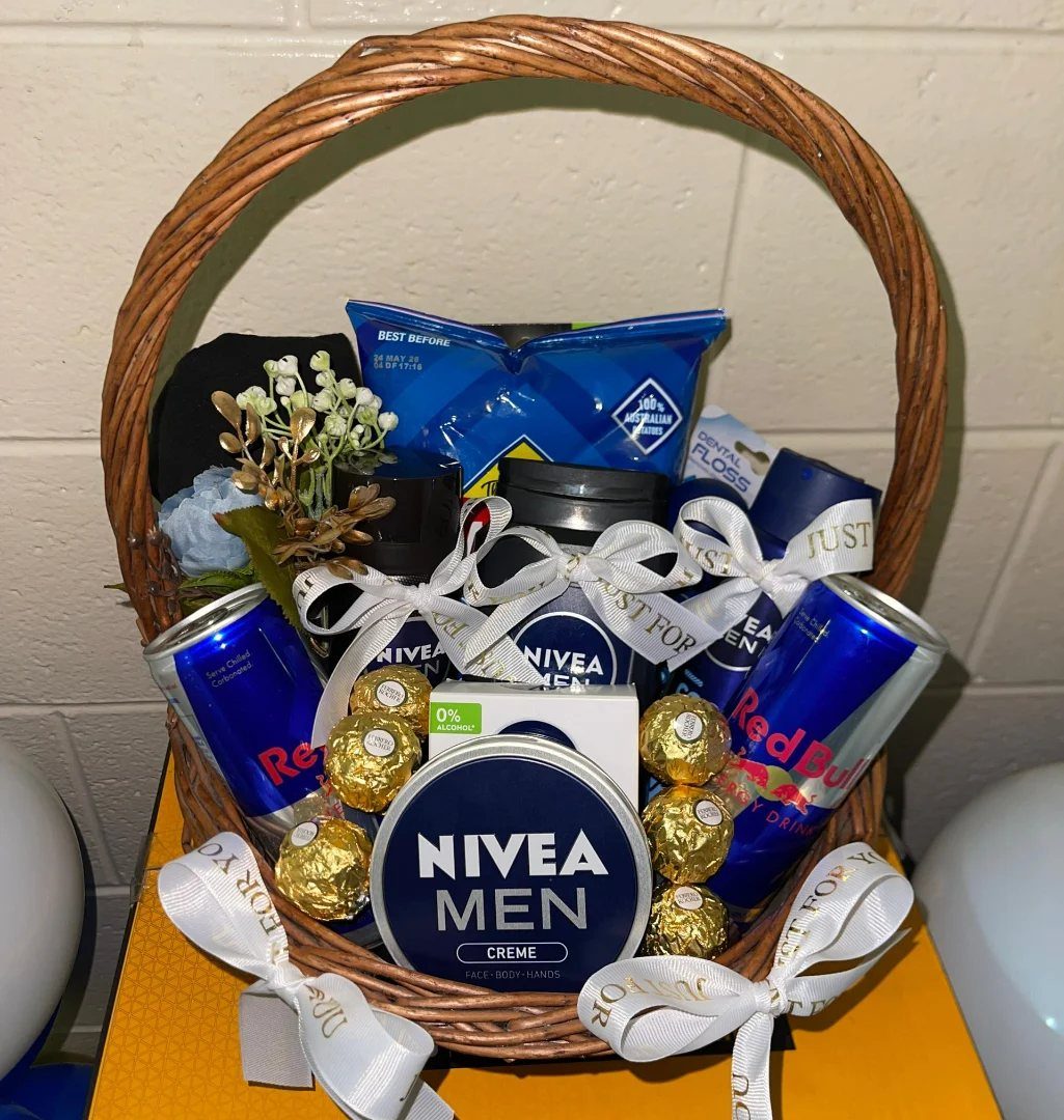 Wicker gift basket containing Nivea Men products, Red Bull cans, and gold chocolates.
