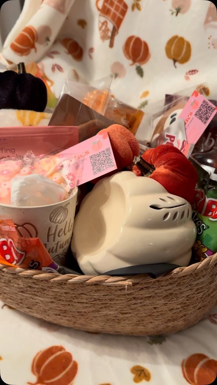 Woven gift basket filled with autumn treats and a pumpkin ceramic warmer.