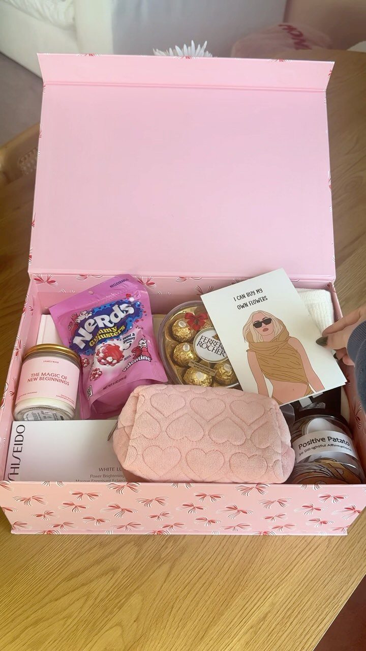 Pink gift box filled with skincare, chocolates, candy, and a plush heart pouch.