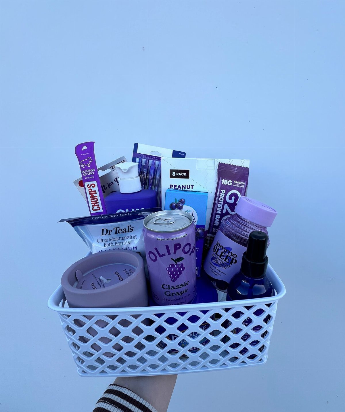 White lattice basket filled with purple themed self care products and snacks.