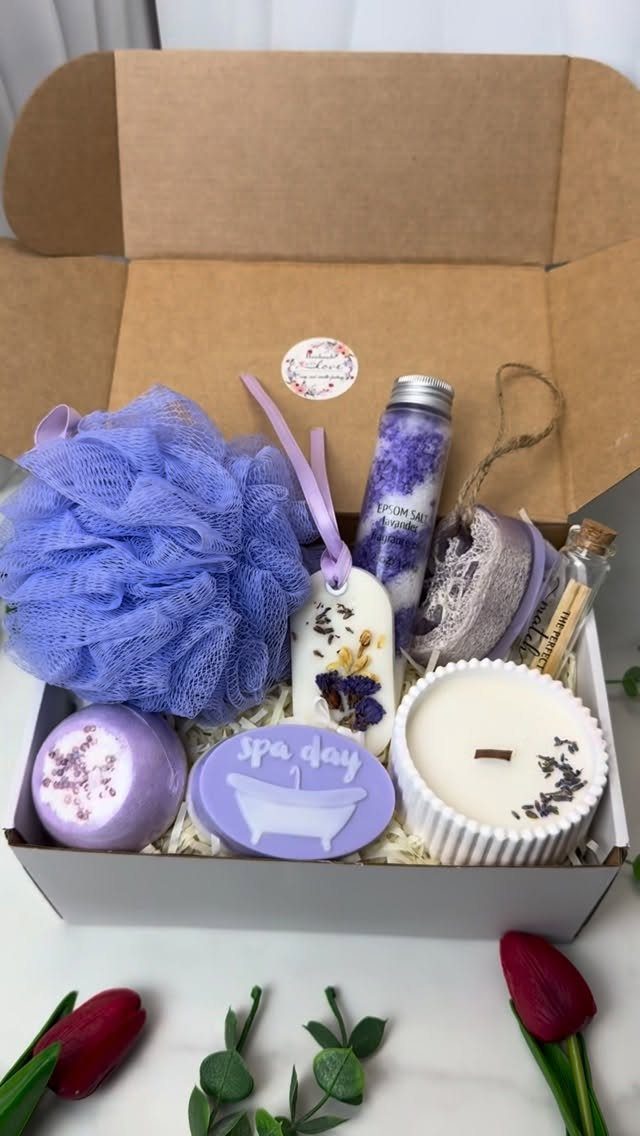Self care gift box with purple bath loofah, candle, and spa themed soaps.