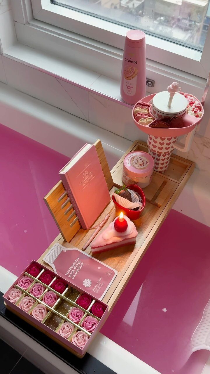 Wooden bathtub tray with pink roses, a book, and a candle on pink water