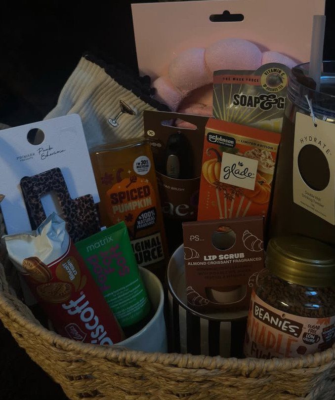 Woven basket filled with candles, skincare products, and snacks for self care.