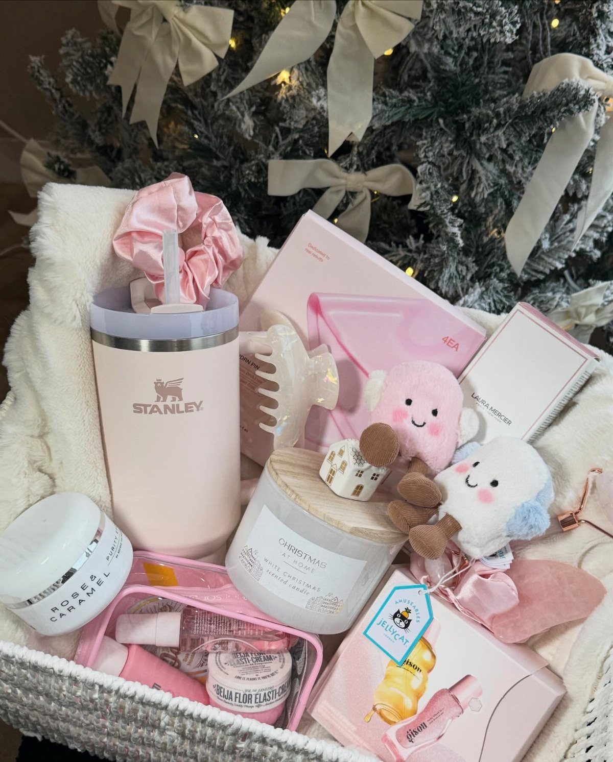 Self care basket filled with pink beauty products, a tumbler, and plush toys.