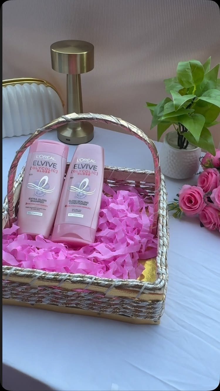 Wicker basket filled with pink shredded paper and hair care product bottles.