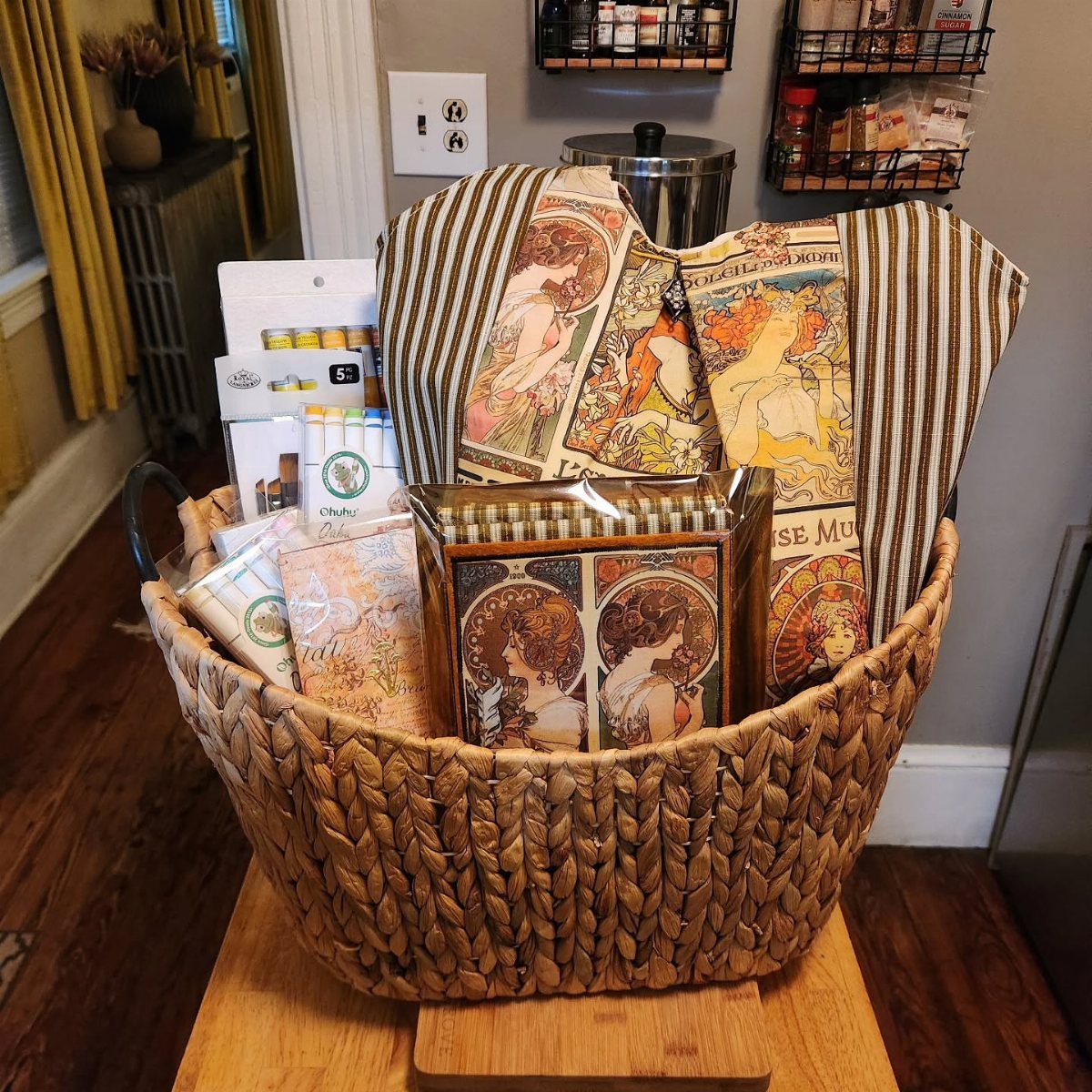 Woven wicker basket filled with colored pencils, sketchbooks, and art supplies with decorative fabric.