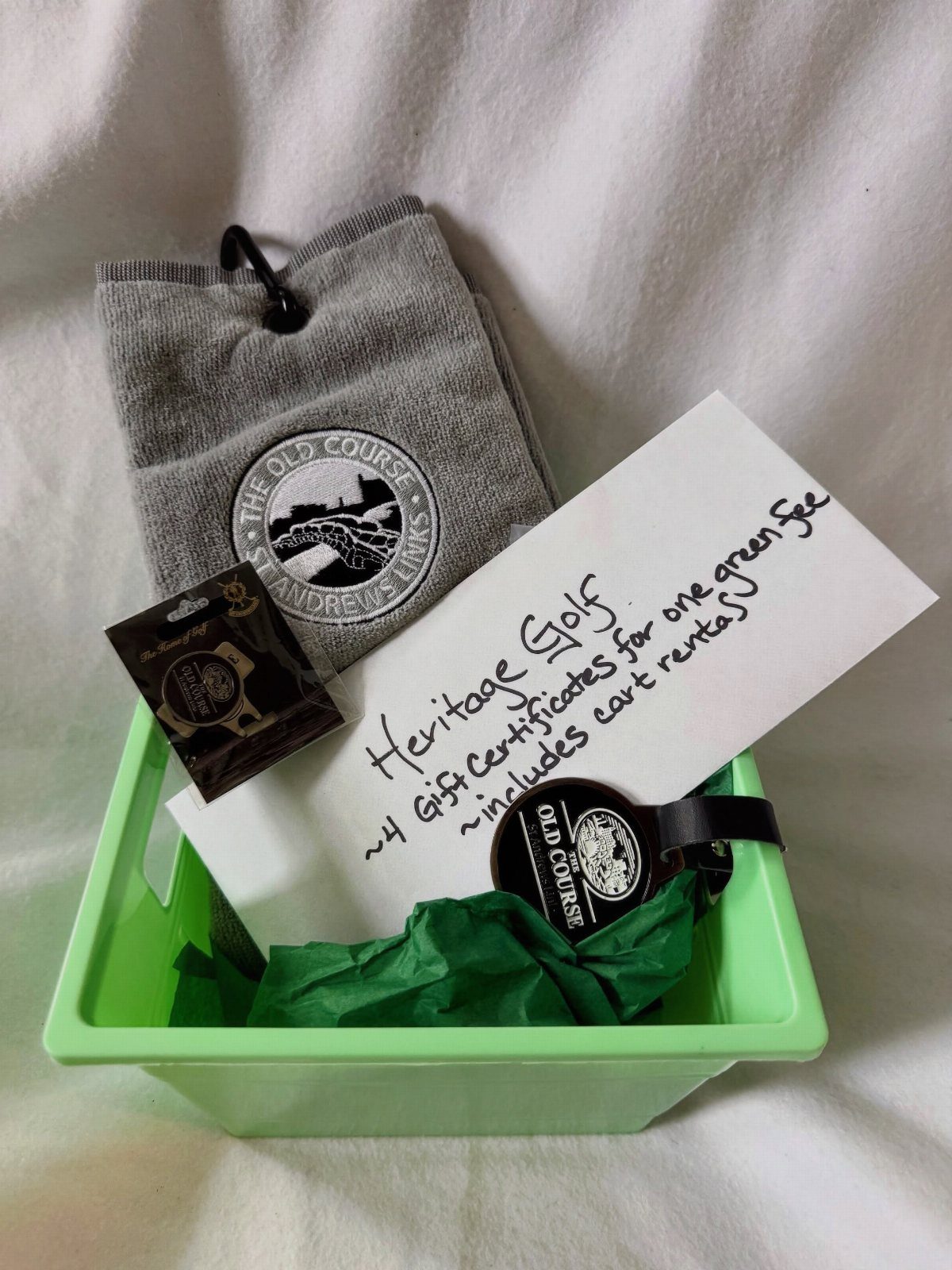 Golf themed gift basket with grey towel, gift certificates, and green bin.