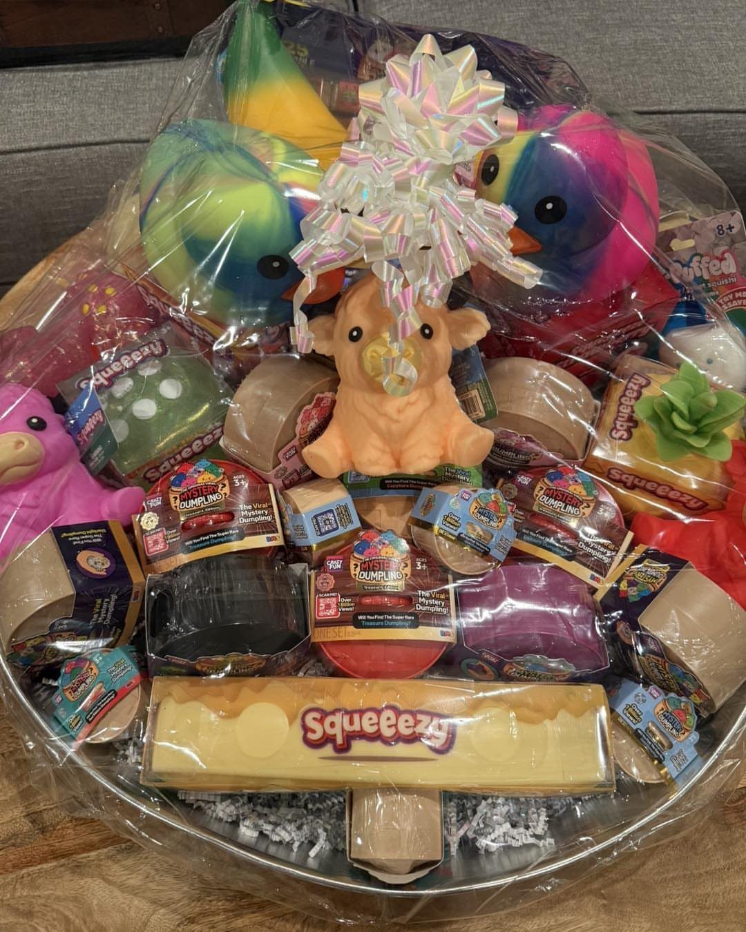 Dog toy gift basket wrapped in cellophane with a decorative bow on top.