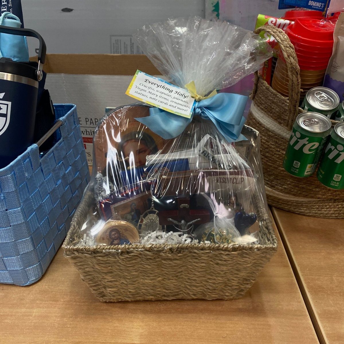 Religious themed gift basket wrapped in cellophane with a blue ribbon on a table
