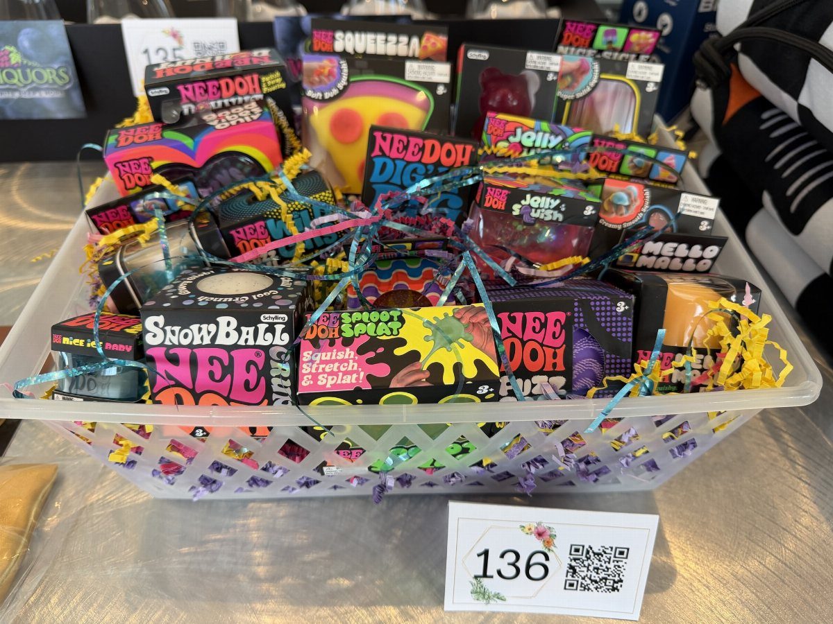 White plastic basket filled with colorful sensory squishy toys and a numbered bid card.