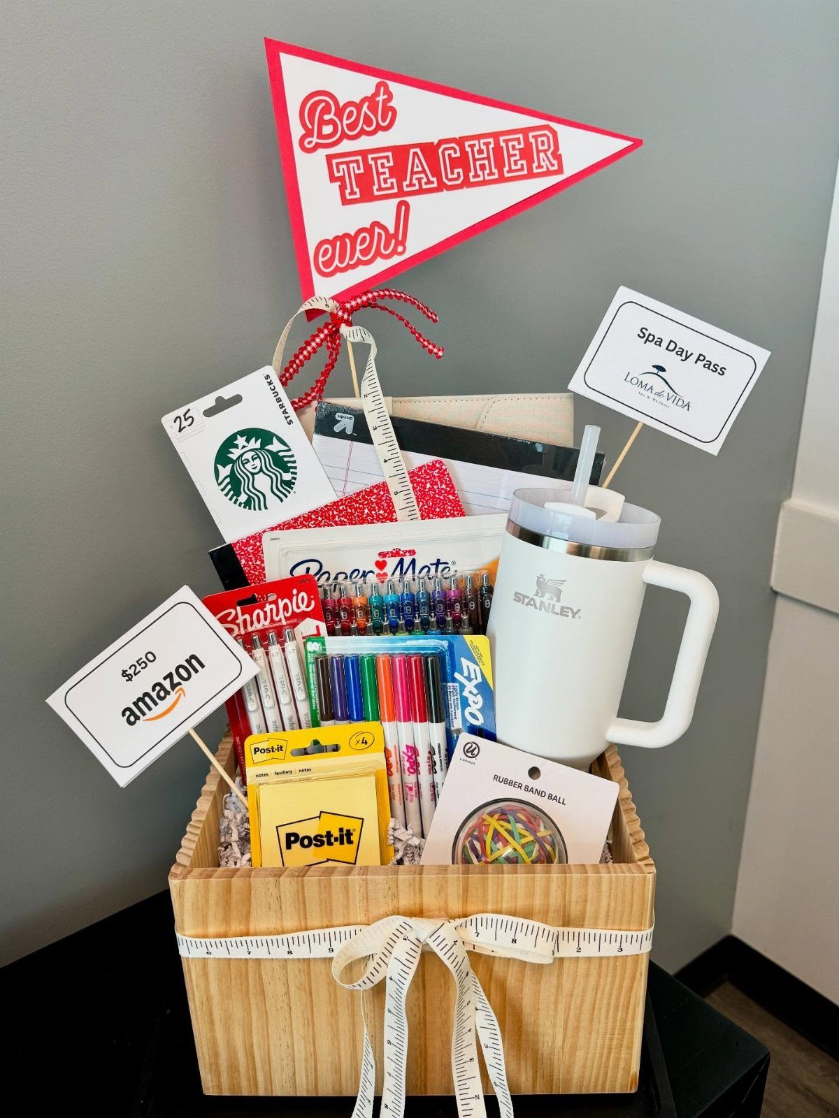 Teacher appreciation gift basket in a wooden crate with school supplies and gift cards.