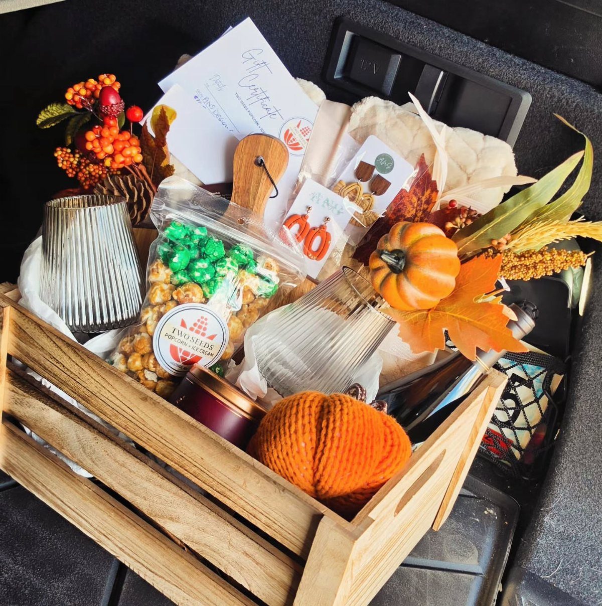 Autumn-themed gift basket in a wooden crate with pumpkins, glasses, and treats.
