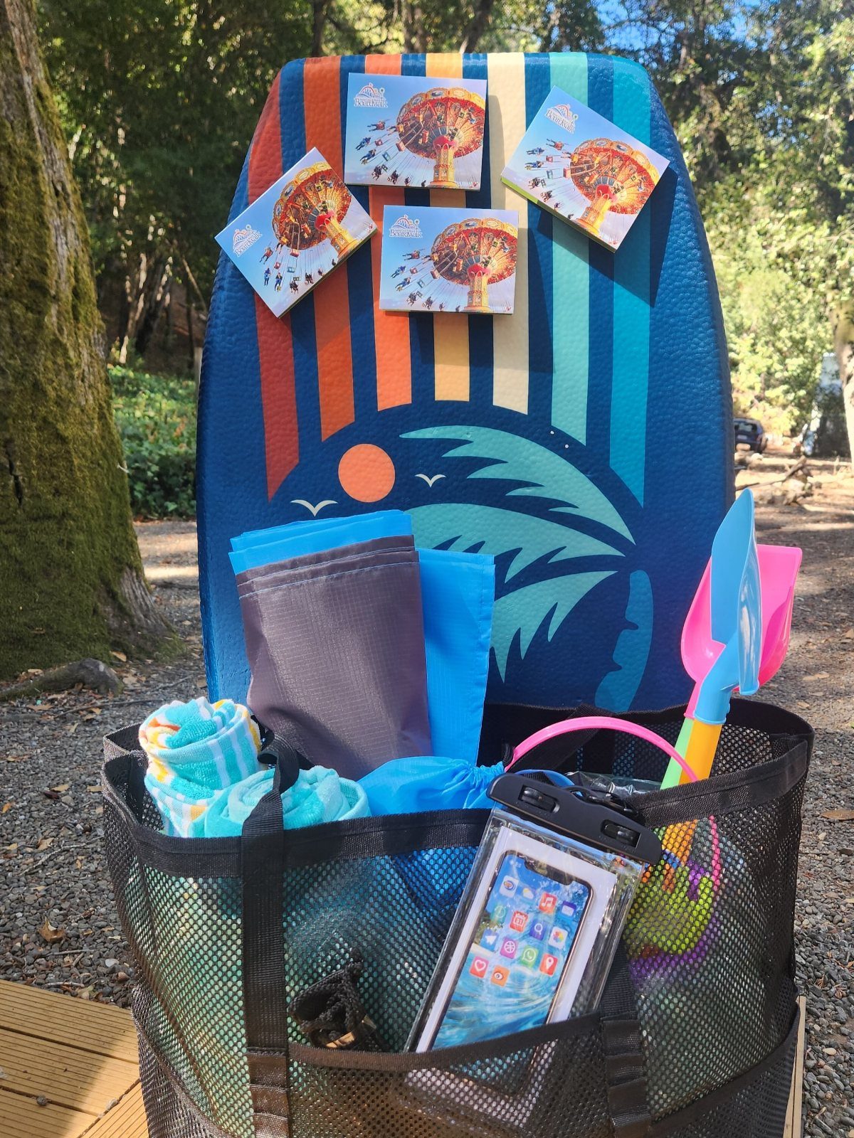 Beach-themed gift basket with boogie board, towels, and sand toys in mesh bag