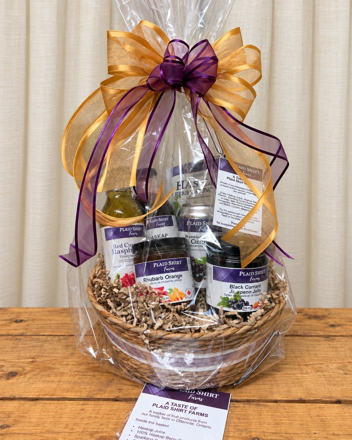 Wicker gift basket with gourmet jams and juices wrapped in clear cellophane.