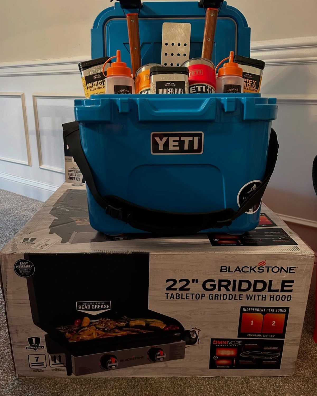 Blue Yeti cooler filled with grilling supplies atop a Blackstone griddle box.