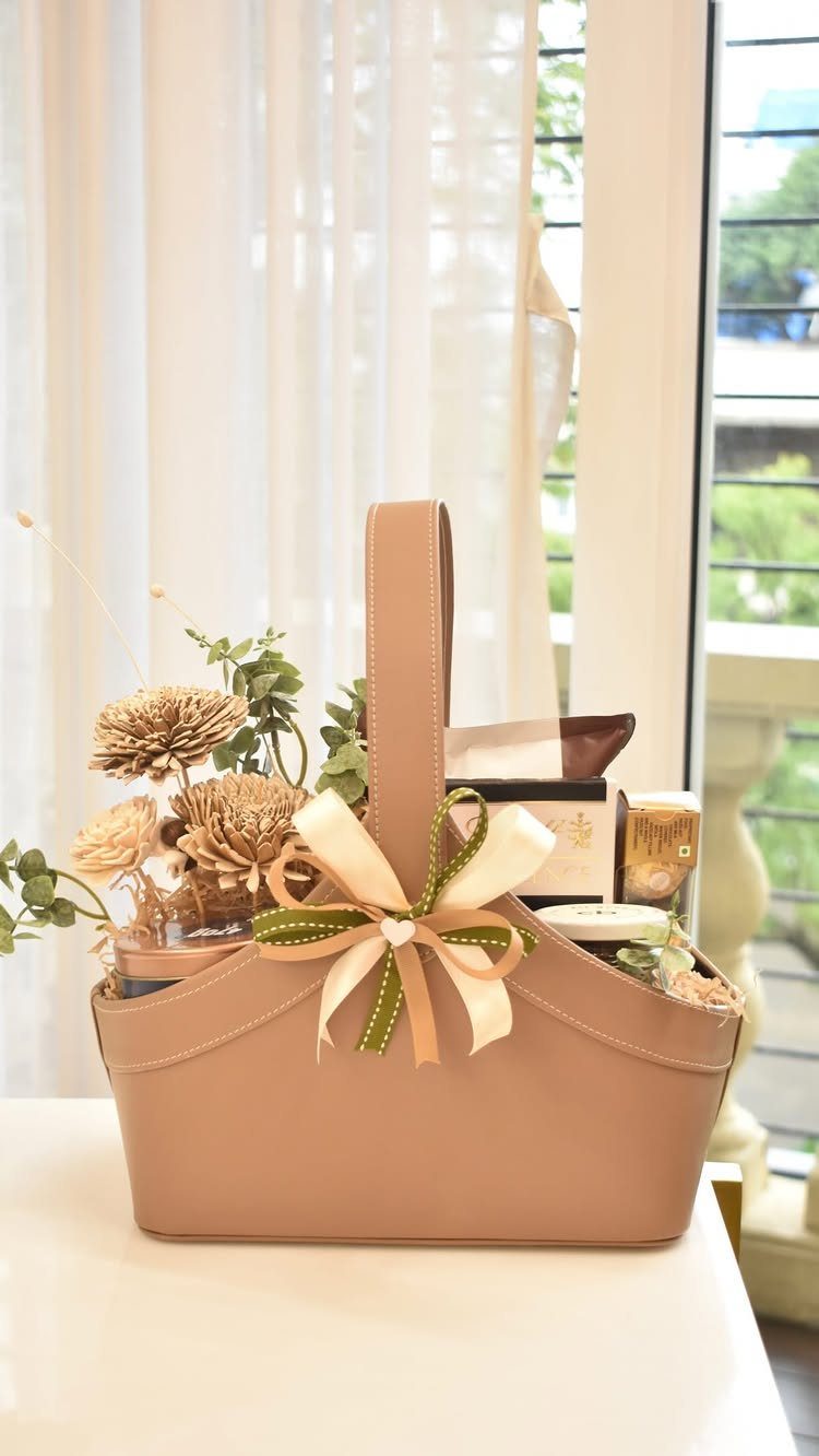 Tan handbag gift basket filled with dried flowers and beauty products with a bow