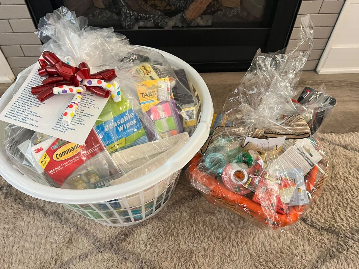 Two cellophane-wrapped gift baskets filled with household supplies and tools on a carpet.