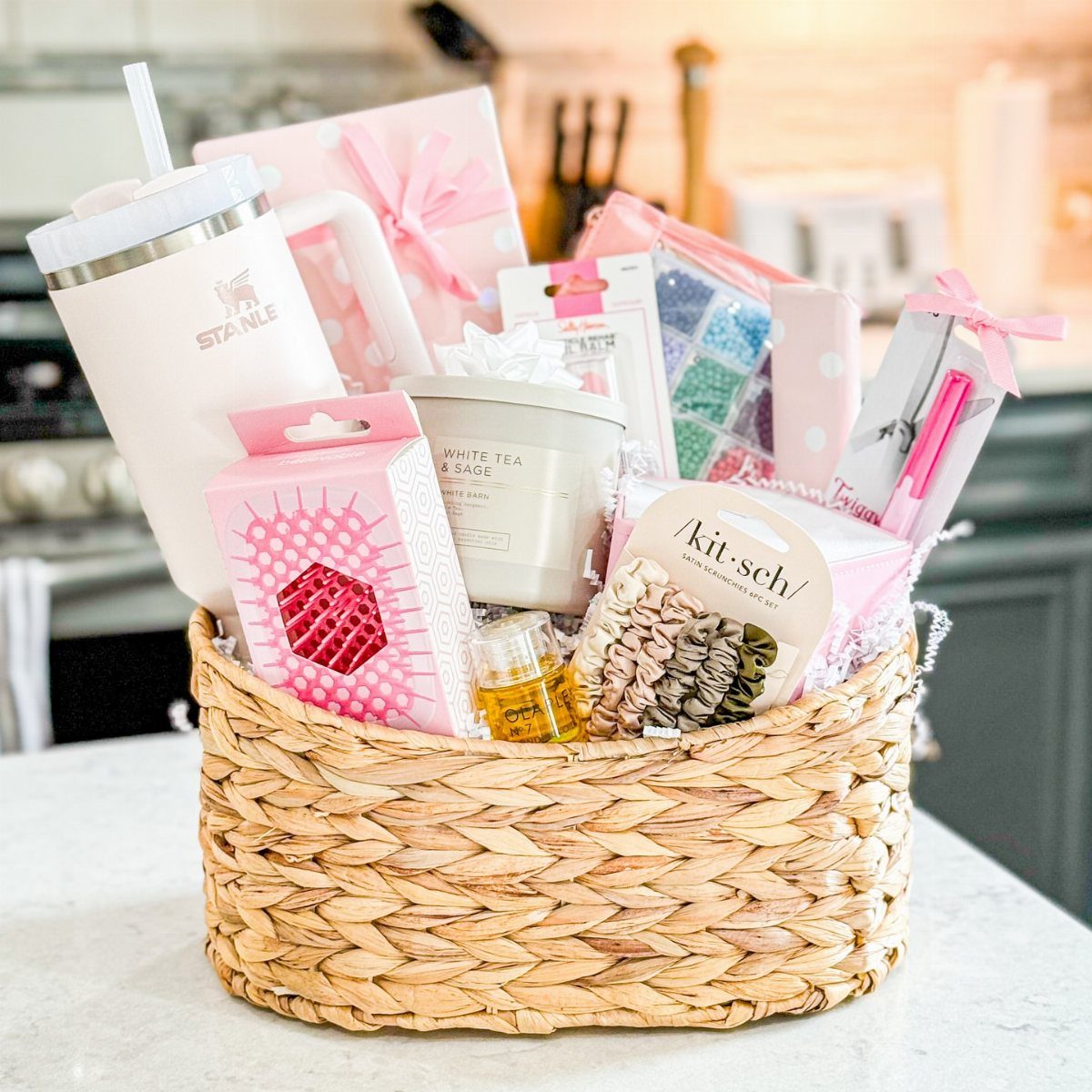 Woven wicker gift basket filled with pink beauty products and a white tumbler.