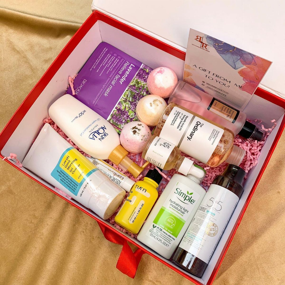 Red gift box filled with skincare bottles, a face mask, and bath bombs.