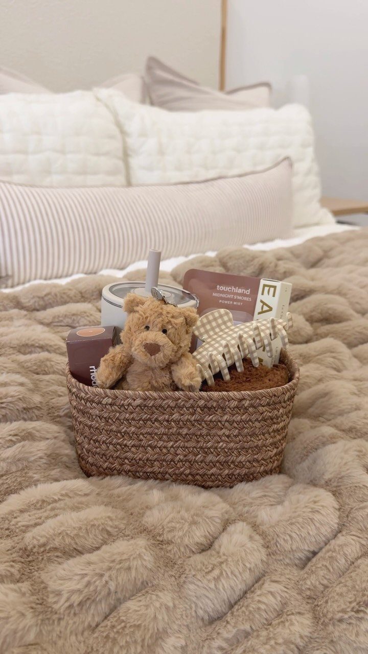 Woven gift basket with skincare products and a teddy bear on a fluffy bed