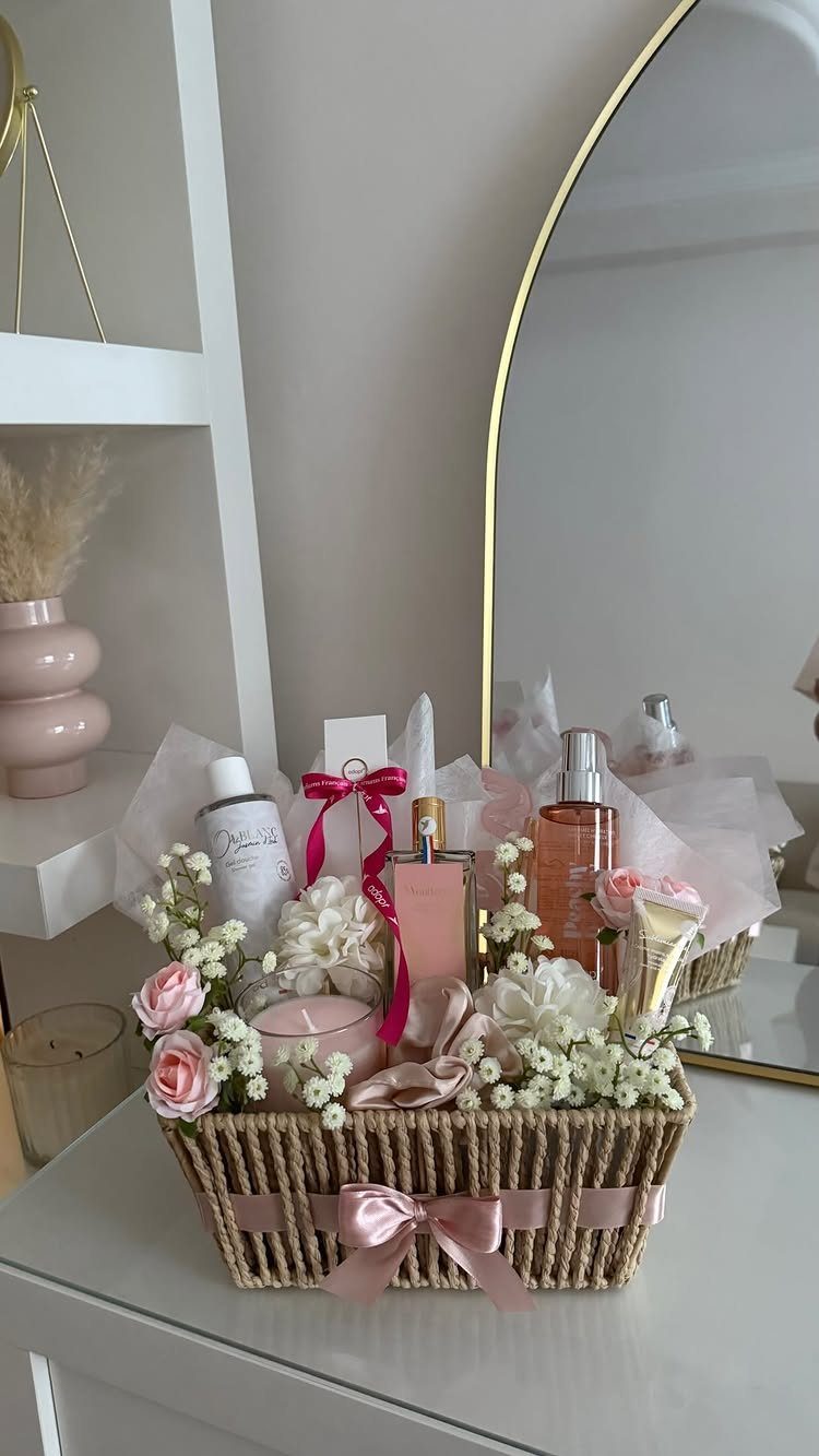 Woven gift basket filled with pink beauty products, perfumes, and fresh spring flowers.