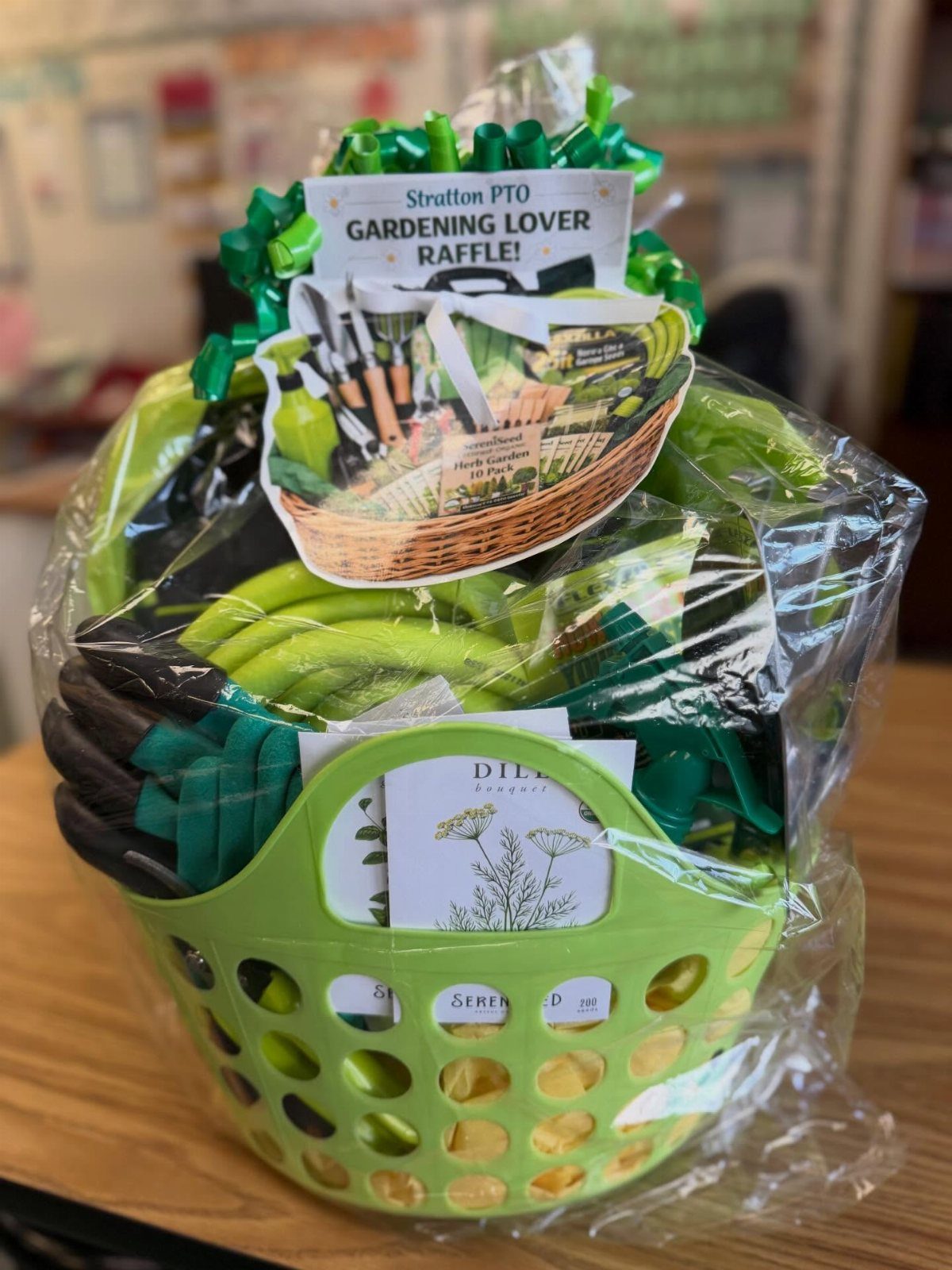 Gardening raffle basket with green tools wrapped in cellophane and a themed sign.