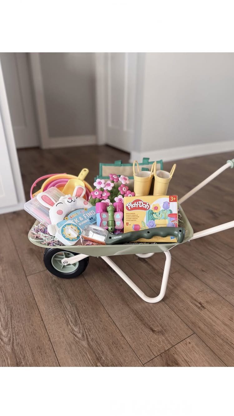 Children's outdoor toys and a bunny plush inside a small white wheelbarrow.