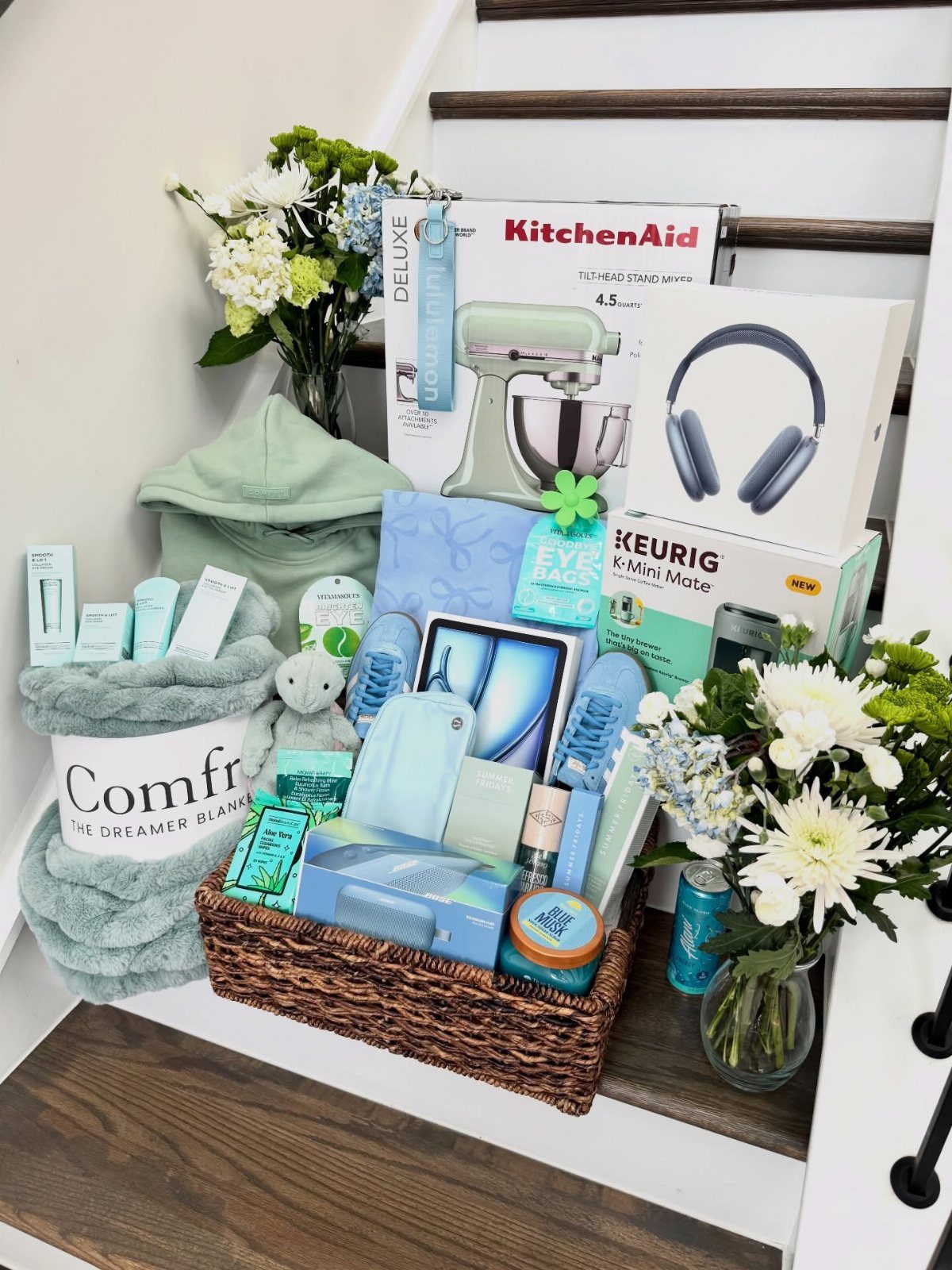 Wicker raffle basket filled with blue spring-themed gifts and appliance boxes on stairs.