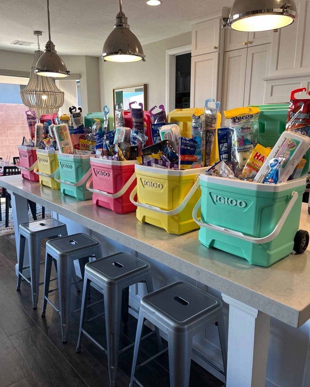 Colorful plastic bins filled with assorted snacks and candies on a kitchen counter.