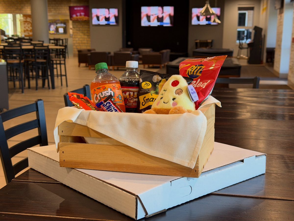 Wooden gift crate filled with snacks and a plush pizza on a table