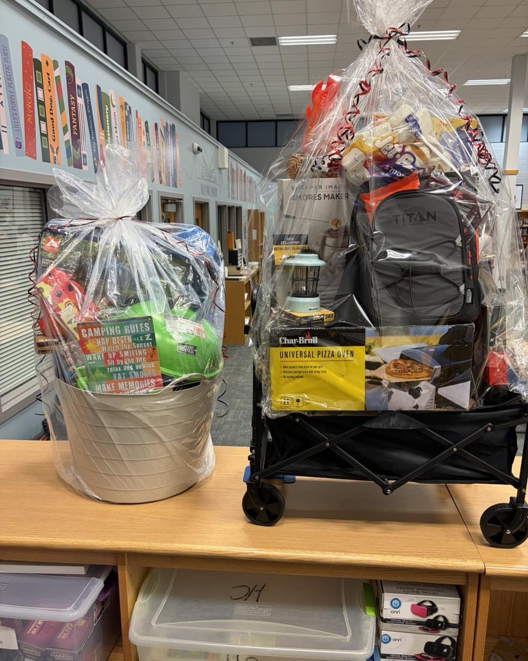 Two camping-themed raffle baskets, one in a tub and one in a wagon.
