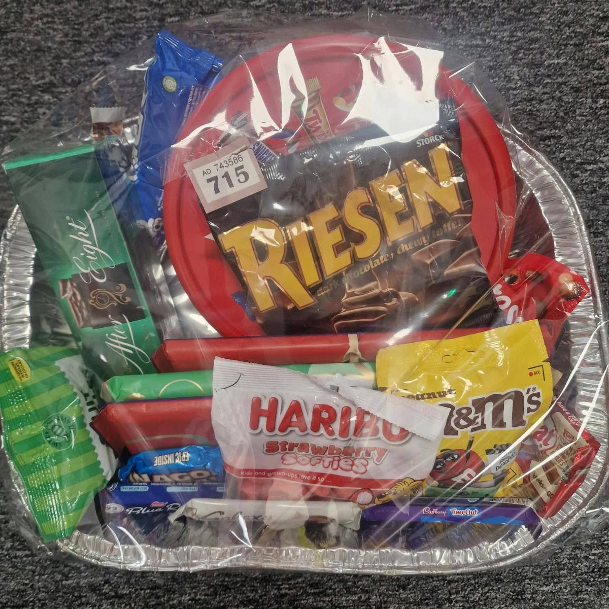 Assorted chocolates and candies in a foil tray wrapped in clear cellophane.