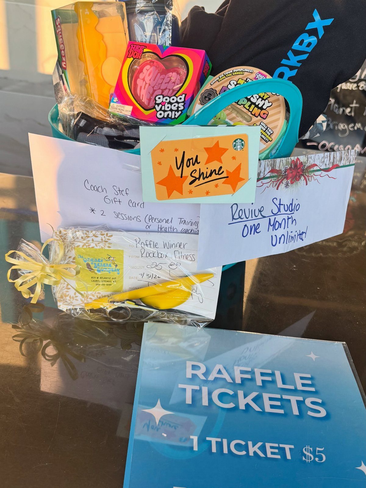 Fitness raffle basket containing gym certificates, a yellow towel, and raffle tickets.