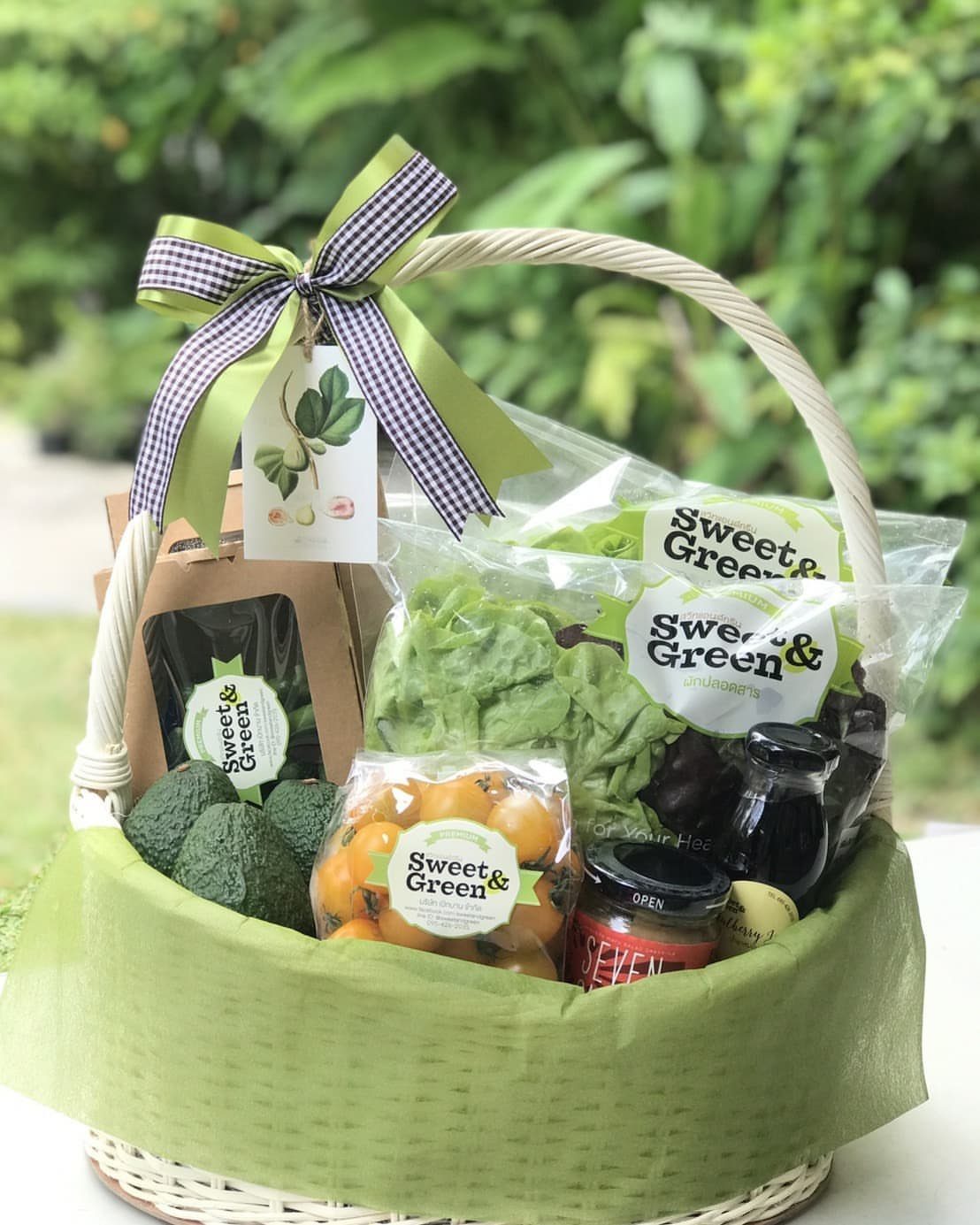 Gift basket filled with fresh produce, avocados, and greens with a checkered bow.