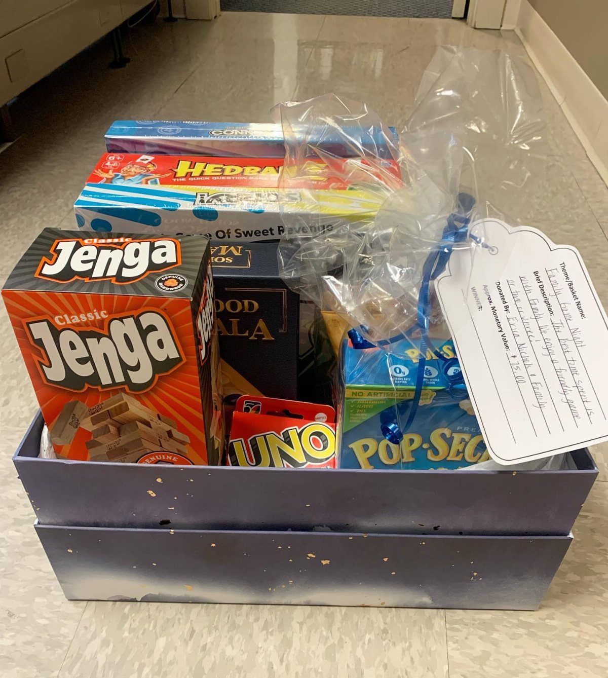 Game night raffle basket containing Jenga, Uno, and other games wrapped in cellophane.